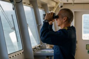 ship captain watching with binoculars