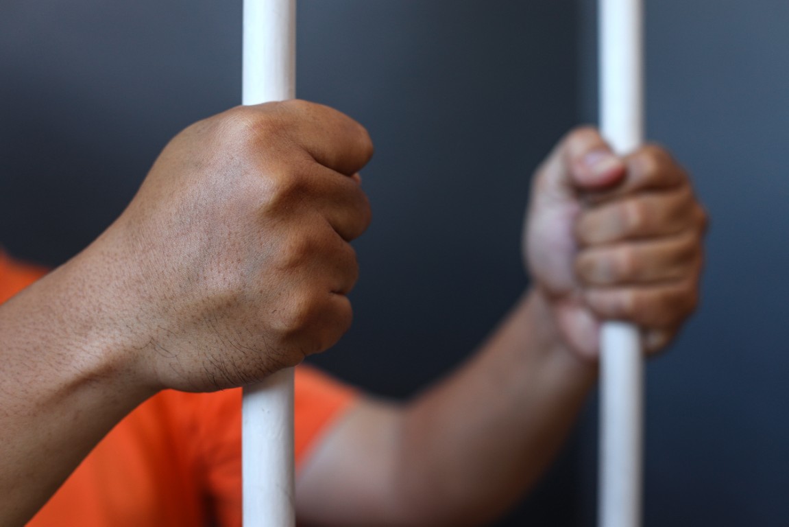 A close up shot of a person's hand behind bars